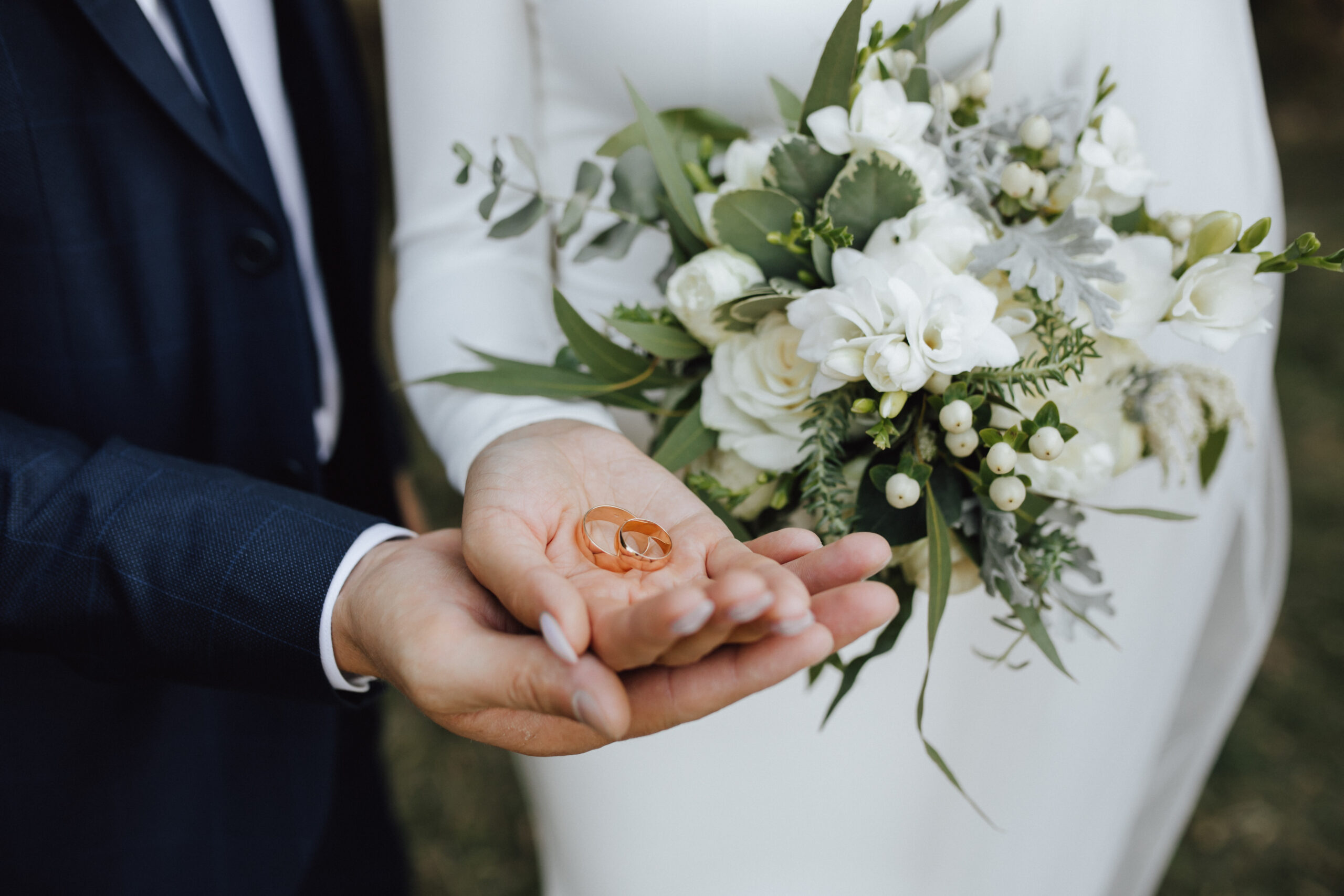 wedding bands in the hands of bride and groom and with beautiful
